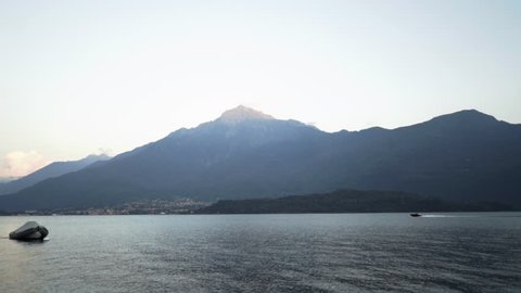 Speedboat Cruises Across Italian Lake at Sunset with Mountains