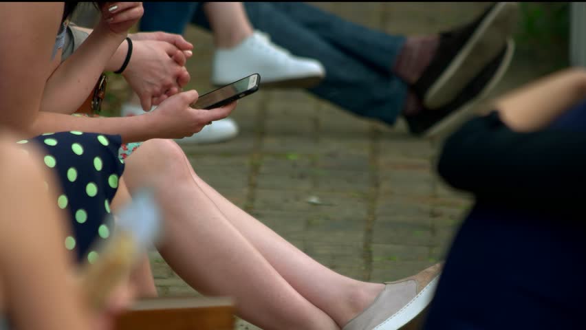 Woman smoking and using smartphone. Close up. Teenagers hanging out.