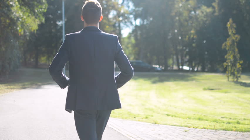 Young businessman walking forward in a hurry to job interview or meeting, back to camera