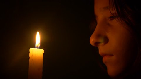 girl teenager with a burning candle. close-up, the face of a girl looking at a candle flame. 4k, slow motion