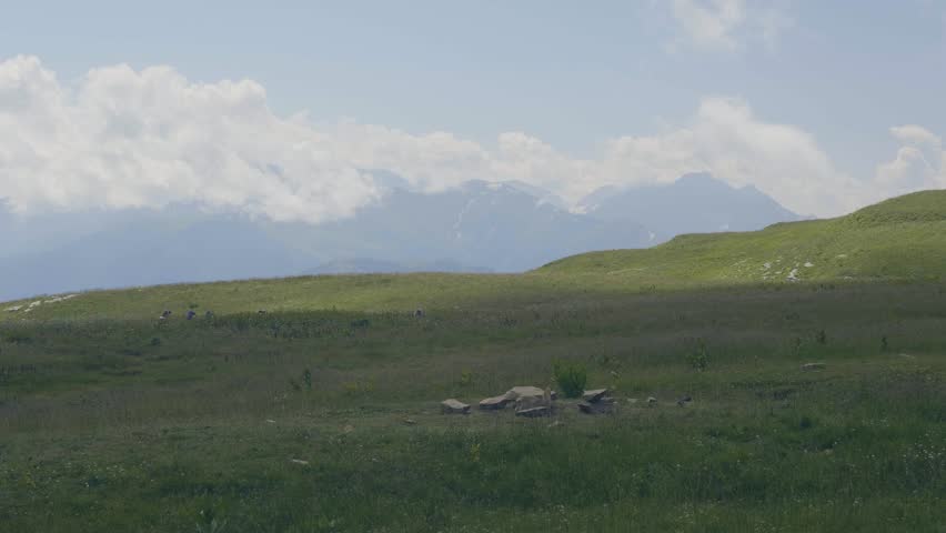 Tourist people walking on green meadow on mountains landscape background