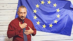Politician man making a speech at press conference or meeting EU flag in background
