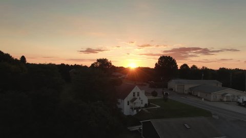 A slow rising aerial establishing shot of a sunset over the western Pennsylvanian countryside. Pittsburgh suburbs.  	