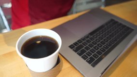 Man using laptop, scrolling on mousepad, coffee cup in foreground.