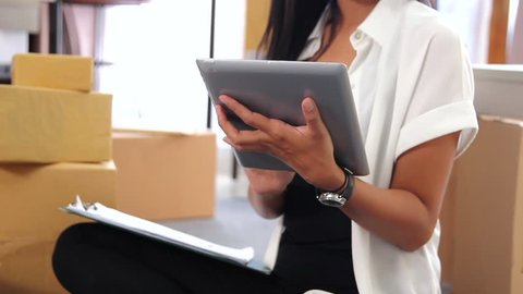 Young woman with online business working using tablet at home and check shipping packages