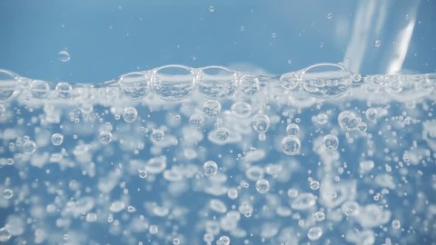 Amazing close up shot of water pouring into a glas in slow motion with a lot of air bubbles