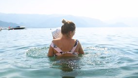 4k video of young mother playing and lifting her toddler son in sea
