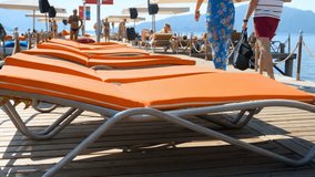 4k video of sunbeds and people relaxing on wooden pier on sunny day day at sea beach