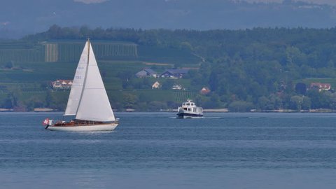 Sailing boat is crossing passenger ship at lake Bodensee, close to Altnau. German shoreline in background. CH Switzerland. 13th Sept.2018