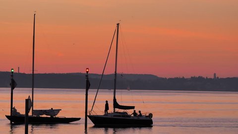 sailing boats passing by at pier in sunset at harbor Altnau. Konstanz city at horizon. lake Bodensee, CH Switzerland. 11th Sept.2018