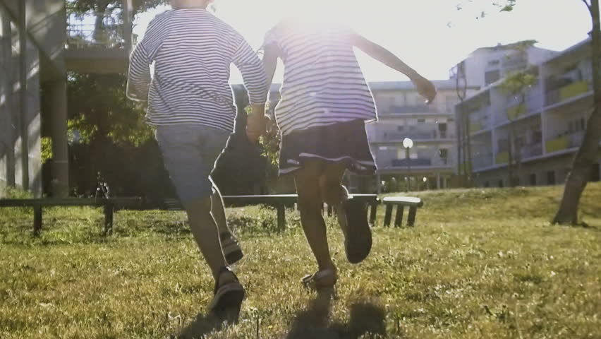 Kids holding hands and running in summer with sunlight. Rear view of children having fun on lawn. Slow motion. Girl jumping over obstacle on playground. Childhood concept Royalty-Free Stock Footage #1016426143