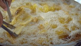 Slow motion clip of chef cooking food in the kitchen. Deep frying crispy banana sliced frying in big pan, Popular thai dessert.