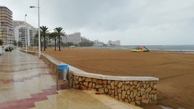 A stormy and raining day by the Mediterranean sea. The video was shoot from the promenade of the famous and touristic El Raco beach located in the coastal town of Cullera, in Valencia, Spain, Europe.