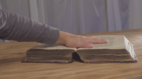 A man's palm on a old book, an oath on the bible. Top view from above