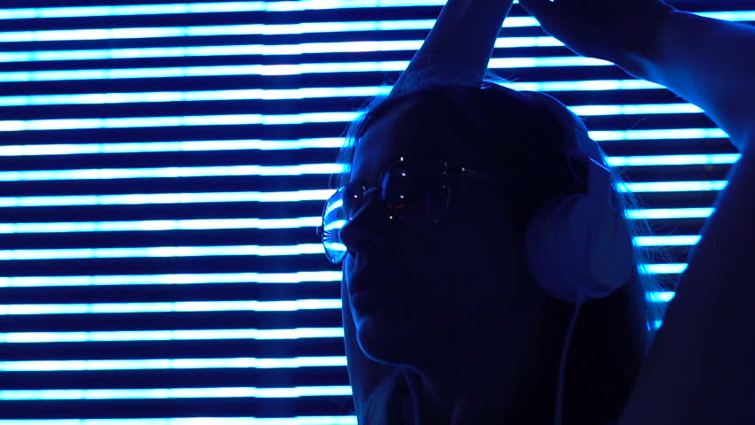 Young woman in headphones on illuminated background, urban entertainment, relax