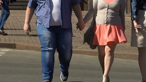 Fat couple in love crossing street holding hands, obesity problem in society