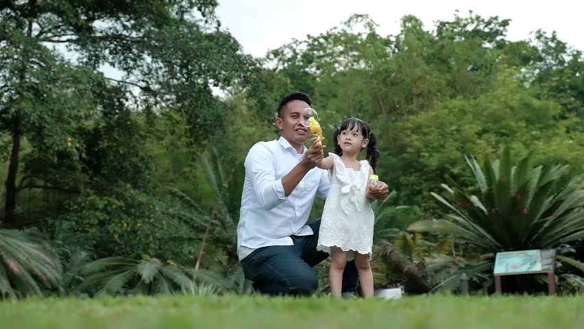 An Asian father and his daughter enjoy quality time at the park in slo-motion
