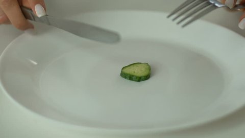 Person slicing cucumber, undereating and anorexia, strict self-restriction