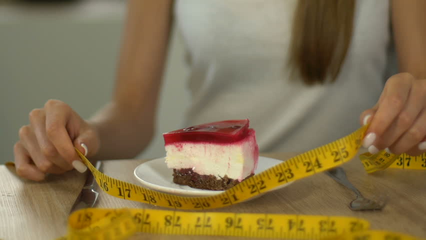 Skinny girl measuring piece of cake with tape-line, calculating calorie intake Royalty-Free Stock Footage #1016456395