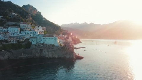 The sun shines on the beautiful city of Atrani, with a clear view of the cliffside road- Aerial shot.