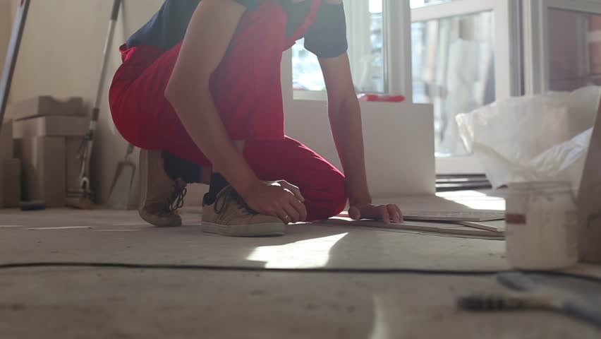 Close look at the constuction worker laying down the tile on cemented floor.