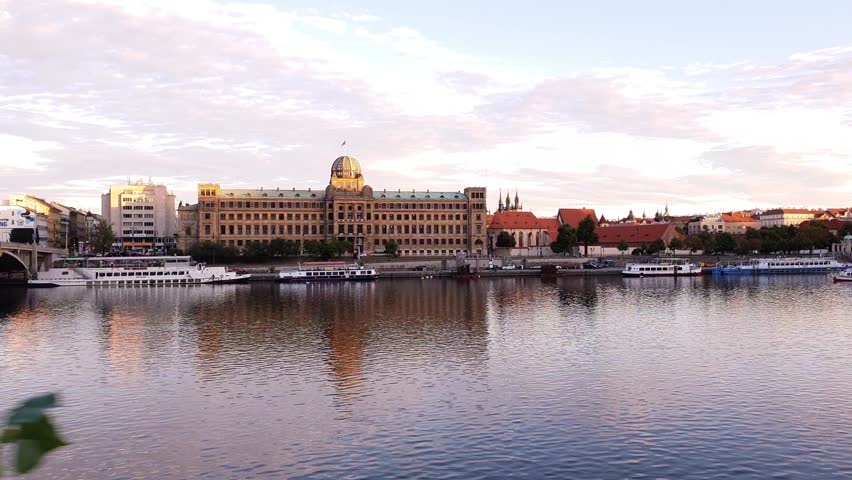 View of Ministry of Industry and Trade in Prague. Alongside the river, with a boat passing. Shot in goldenhour.
