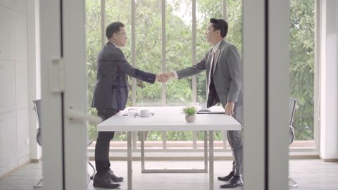 Slow motion - Handshake to seal a deal after a job recruitment meeting. Two asian confident businessman shaking hands during a meeting in the office, success, dealing, greeting and partner concept.