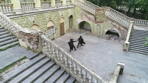 Air shot musketeers fight in a duel air of an ancient building with a ladder