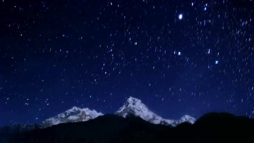 Star trails on a dark blue sky, over a icy snowy mountain at Pokhara Nepal