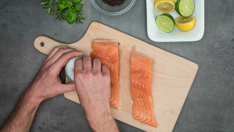 Man cuts small steak from salmon fish. Top view on food ingredients, stop motion animation. Shot B (see also shot A from SIDE).