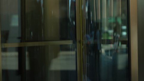 Close up of hands pushing a revolving glass door in a downtown city setting.