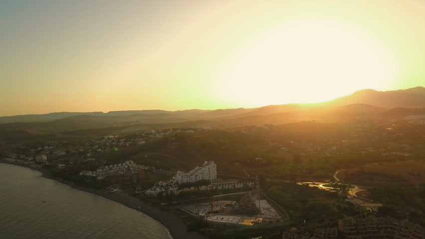 Drone panoramic footage of sunset behind the Rock of Gibraltar showing the beaches and resorts.