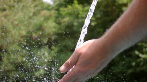 Hand under a stream of water from a garden hose