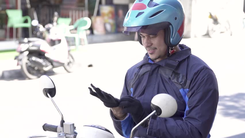 footage of motorcycle taxi driver wearing a jacket for safety riding on the side of the road