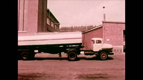 CIRCA -1964 - Delivery trucks and homogenizers are seen at a dairy plant in Belgium.