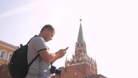 Travel and technology. Happy lifestyle tourist man looks the navigator smartphone taking selfie with backpack. slow motion video. on Red Square in Moscow, Russia. tourist journey travel man in Russia