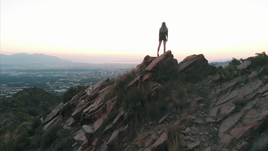 Aerial shot of woman hiker on top of mountain Salt Lake City Utah sunset
