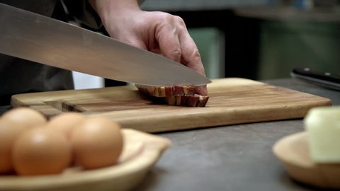 Chef slicing raw pork bacon on wood board