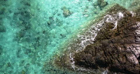 Aerial view of blue sea surface with waves near stone shore