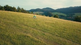 Aerial View Yoga woman is jogging in summer sunny day around trees and mountains background under sun light with blue sky, Drone 4K Video
