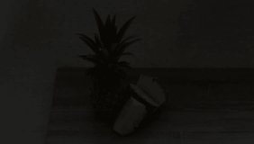 Video pineapple and juice in a glass stand on the table, the light passes from bright to dark.