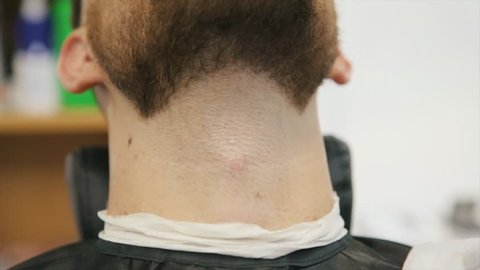 Professional barber with open cutthroat razor shave the beard in the Barbershop. Man hairdressing with straight razor cuts the hair on face. Slow Motion. Close Up