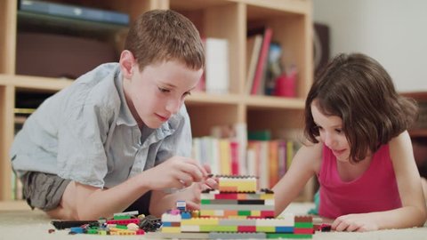 Two kids playing with lego bricks at home
