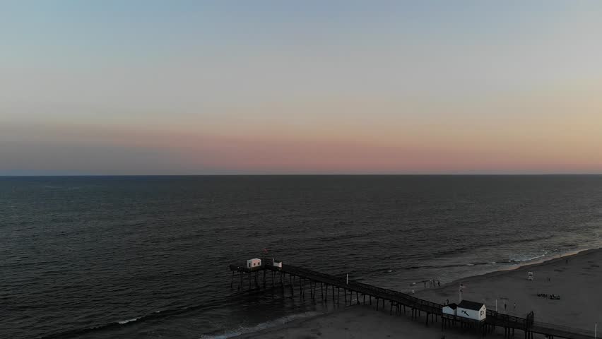 A beautiful aerial view of the Ocean City New Jersey Fishing Pier on 14th street. The summer sun setting in the background. Beautiful colors.
