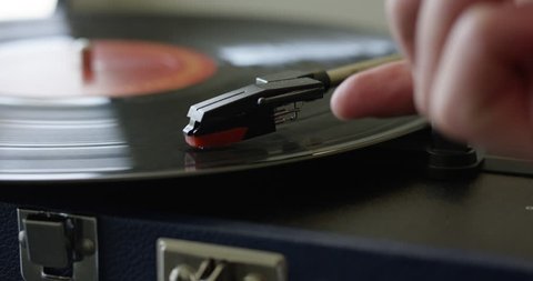 Man fumbles to remove retro record player needle from vinyl - close up scratching record