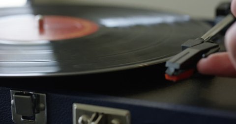 Man places retro record player needle onto vinyl - close up
