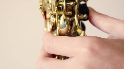 Details of a man playing a golden saxophone. A wind instrument seen very close to the camera.