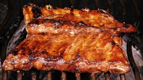 UHD closeup shot of marinated spare ribs cooking on a barbecue grill