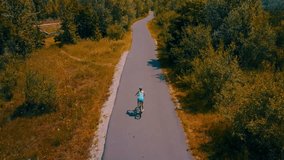 Aerial View cyclist rides on the road on summer sunny day light in the trees and mountains outdoors background, Drone 4K Video