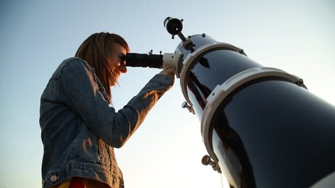 Young woman looking at the sky with astronomical telescope.
